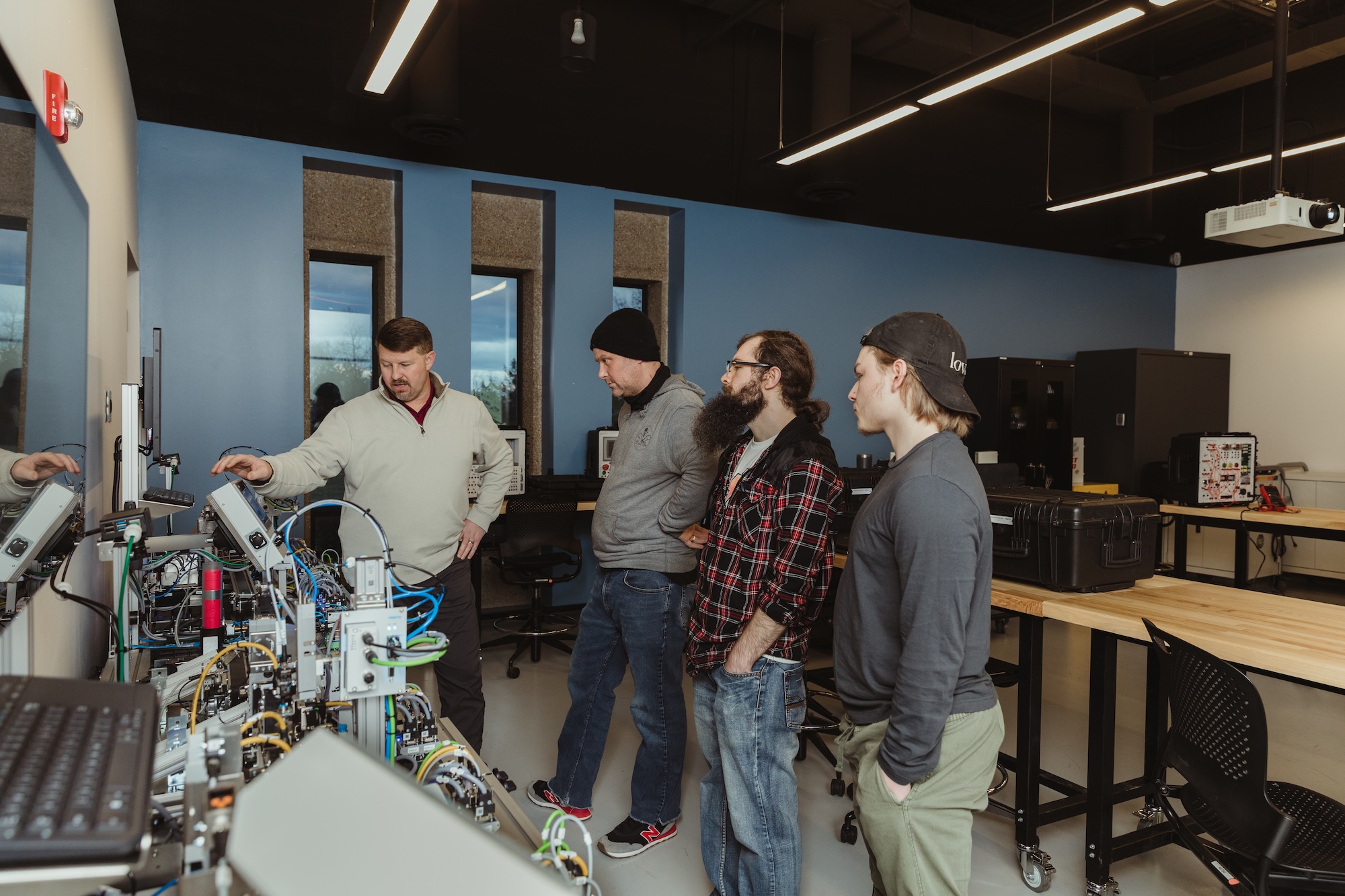 An instructor demonstrating industrial automation equipment to mechatronics students